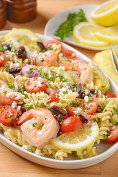 a plate of pasta with shrimp, tomatoes and olives