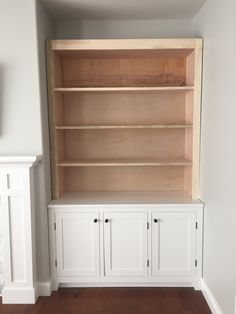 an empty room with white cabinets and wood floors