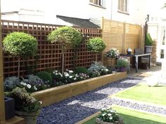 a garden with flowers and plants in the middle of it, next to a house