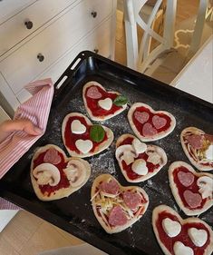 heart shaped pizzas on a baking tray ready to be baked in the oven for valentine's day