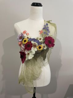 a white mannequin with flowers on it's chest and scarf around the neck