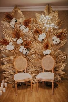 two chairs sitting next to each other in front of a wall with flowers on it