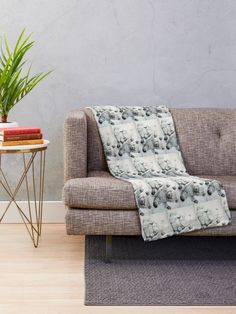 a couch with a blanket on it next to a table and potted plant in the corner