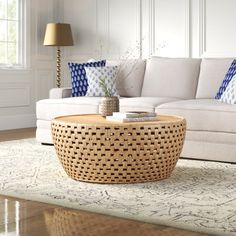 a living room with white couches and blue pillows on the table in front of it