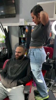 a woman standing on top of a man's head in a barbershop