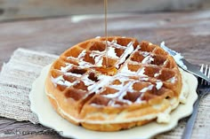 a waffle being drizzled with syrup on top of a white plate