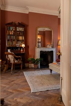 a living room filled with furniture and a fire place next to a book shelf on top of a hard wood floor