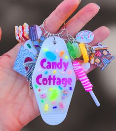 a hand holding a keychain that says candy cottage with lots of candies on it