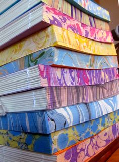 a stack of colorful books sitting on top of a wooden table next to a laptop computer