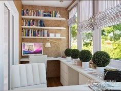 a computer desk sitting in front of a window next to a book shelf filled with books