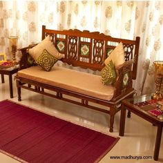 a wooden bench sitting next to two tables with pillows on top of it and a rug in the middle