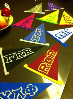 a table topped with lots of colorful pennants next to a bowl of fruit on top of it