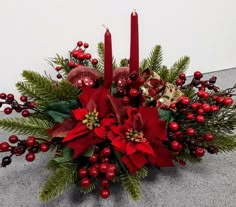 a christmas centerpiece with candles and poinsettis