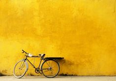 a bicycle leaning against a yellow wall