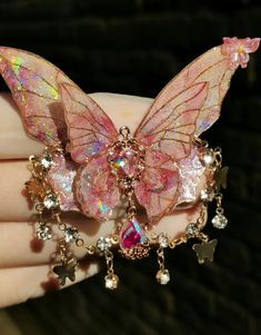 a close up of a person's hand holding a butterfly brooch