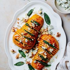 grilled sweet potatoes topped with goat cheese and sage leaves on a white platter