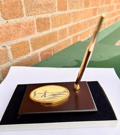 a pen sitting on top of a plaque next to a brick wall