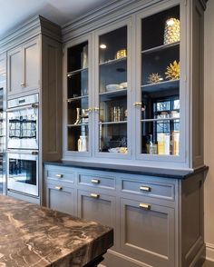 a kitchen with gray cabinets and marble counter tops