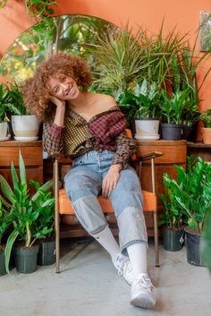 a woman sitting on a bench surrounded by potted plants