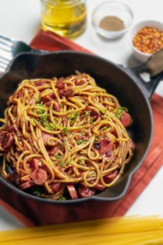 pasta with sausage and broccoli in a skillet next to some yellow pencils