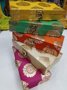 four colorful boxes stacked on top of each other with gold trimmings and designs