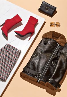 a pair of red high heeled shoes next to a black purse and some accessories