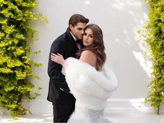 a bride and groom posing for a wedding photo in front of green ivy covered archways