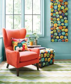 an orange chair and ottoman in front of a blue wall with colorful flowers on it