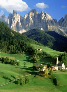 the mountains are covered with green grass and trees, while houses stand in the foreground