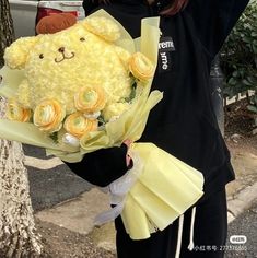 a woman holding a large teddy bear with roses in it's lap and wearing a black hoodie