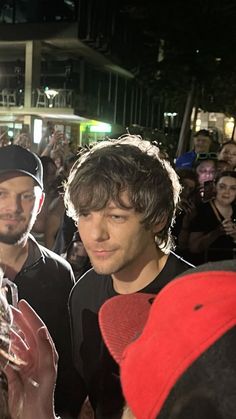 two men standing next to each other in front of a group of people at night