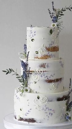 a three tiered white wedding cake with purple flowers and greenery on the top