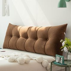 a bed with a brown headboard and pillows on top of it next to a small table