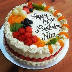 a birthday cake with fruit on it sitting on a table