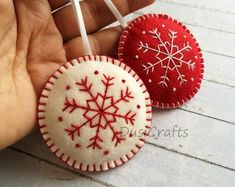 two red and white ornaments are being held by someone's hand