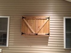 an open window on the side of a house that has shutters and a wooden door