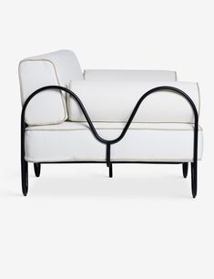 a white couch with black metal legs and arm rests against a white background, the back end is curved