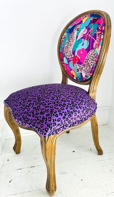 a leopard print upholstered wooden chair with purple and pink fabric on the back