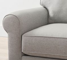 a close up view of the arm and back of a gray couch with wood flooring