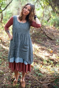 a woman standing in the woods with her hands on her head and looking at the camera