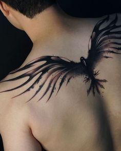 the back of a man's chest with a black bird tattoo design on it