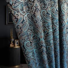 the curtain is open and has a blue paisley pattern on it, along with a black wall