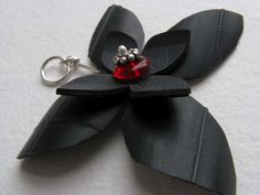 a black flower keychain with a red glass bead on it's center