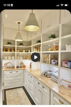 a kitchen filled with lots of white cupboards and counter top space next to a wooden floor