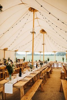 a large tent with tables and chairs set up for an outdoor wedding reception under string lights