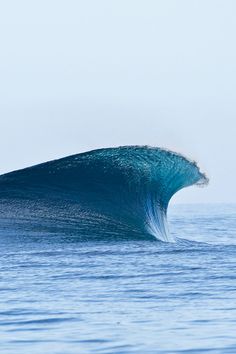 a large blue wave in the middle of the ocean