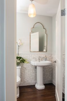 a bathroom with a pedestal sink, mirror and toilette in it's corner