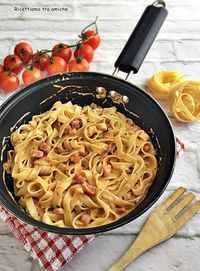 a pan filled with pasta next to tomatoes