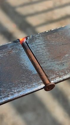 a piece of metal sitting on top of a wooden table next to a burning match