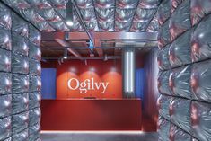 an office with red walls and shiny plastic coverings on the wall, as well as a sign that reads oglyy